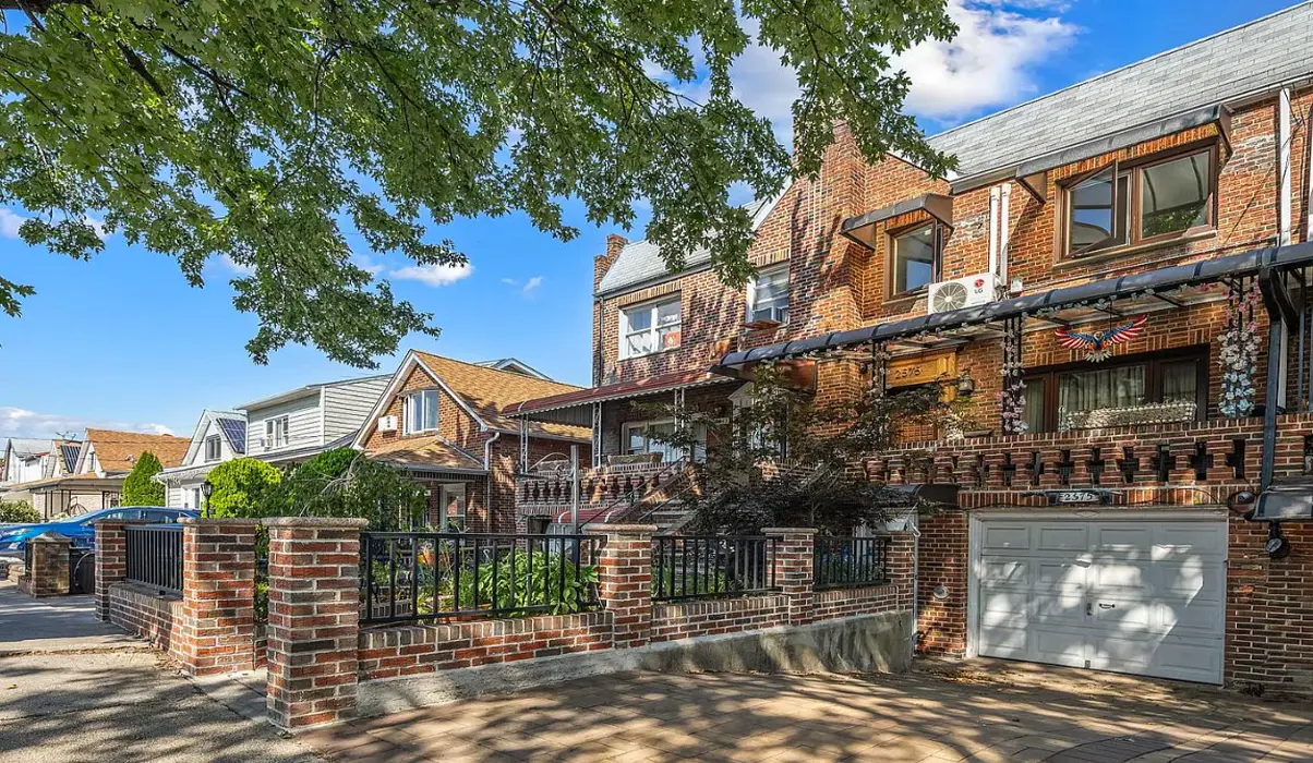 Tree-lined residential street in Sheepshead Bay with brick houses and parked cars